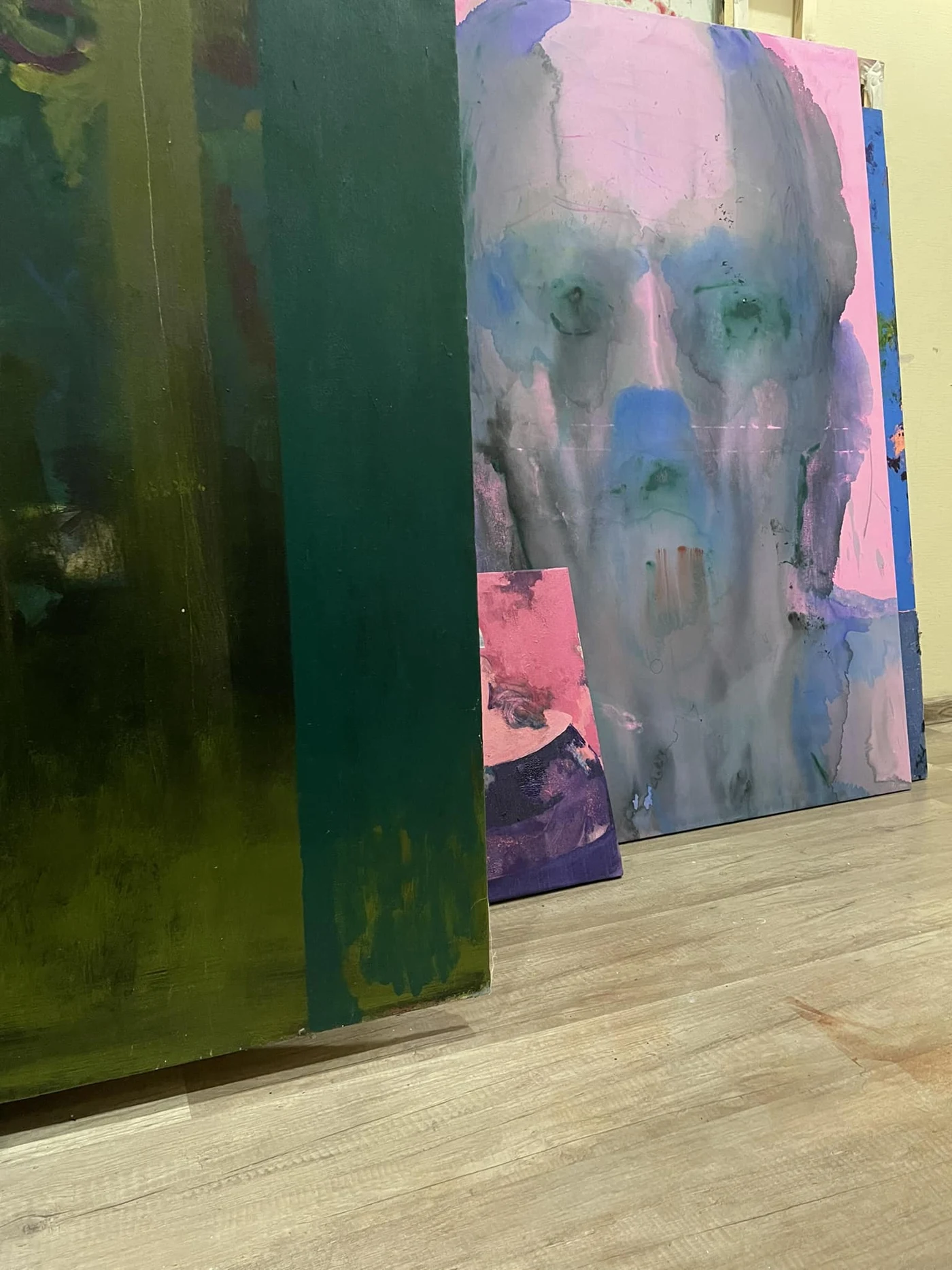 Paintings with green and pink surfaces arranged in the studio